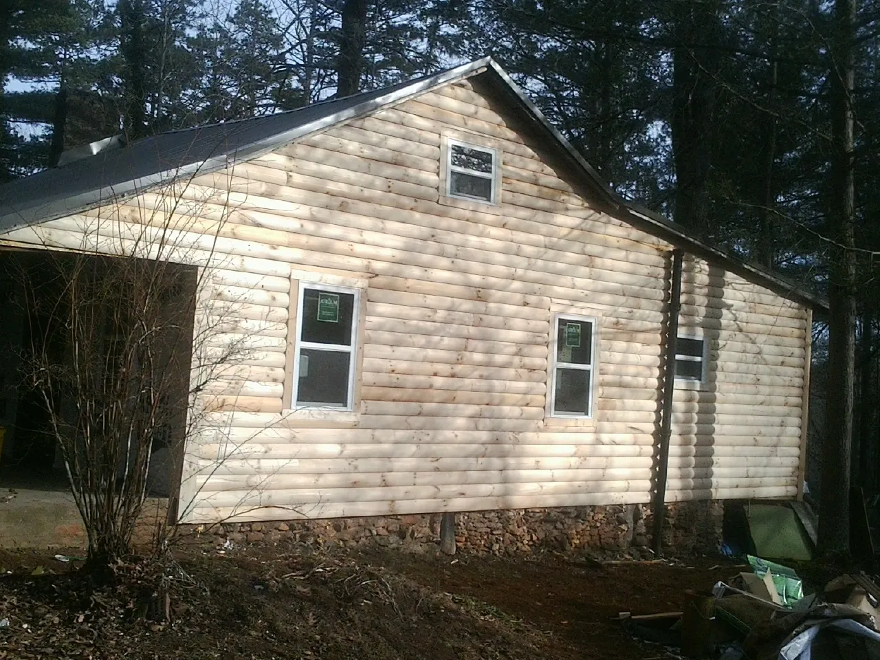 New log siding and dark metal roofing on a gable end in Hamlet