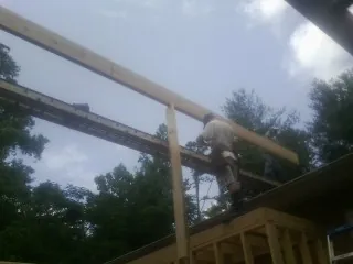 Carpenter setting a ridge beam over a new addition frame — Ice Dam Removal by Roofing Brothers in Hamlet