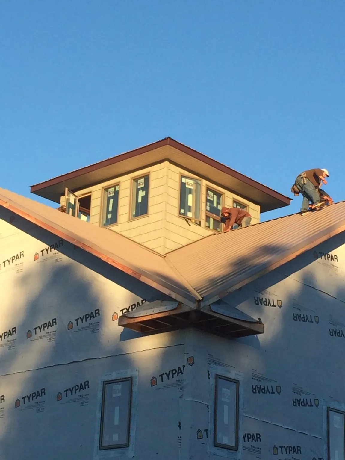 Roofers working around a rooftop cupola on a new metal roof at sunset — Roof Waterproofing in Hamlet by Roofing Brothers